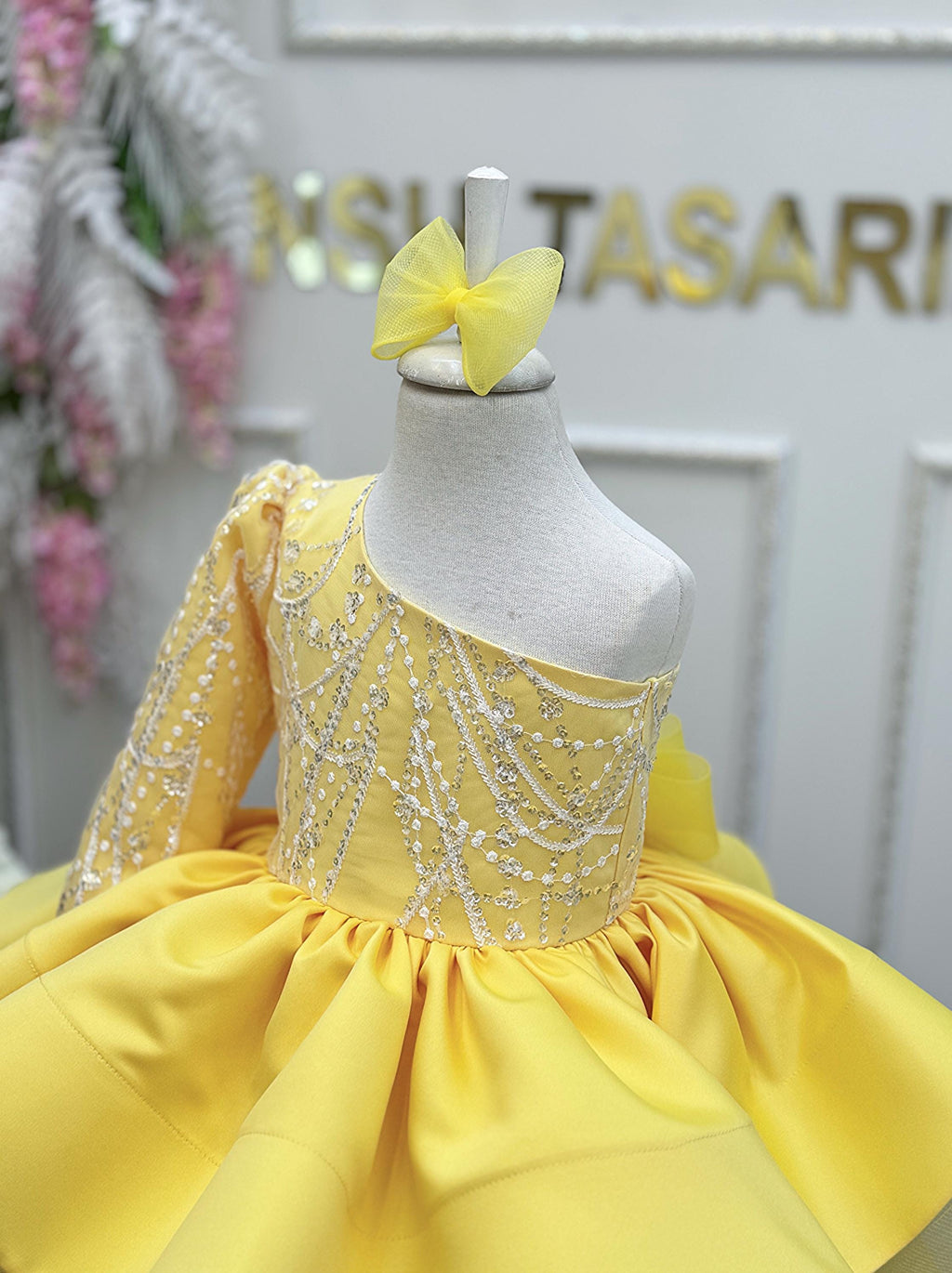 Close-up of the shiny silver lace bodice and matching hair accessory on a one-shoulder toddler sundress.