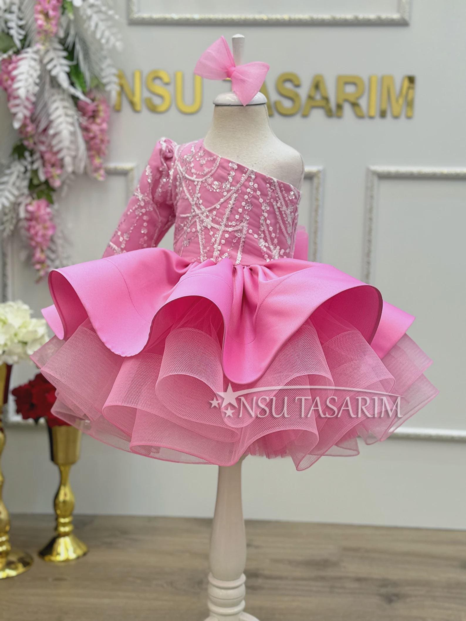 Toddler princess dress in pink tulle with a one sleeve design, perfect for a fairy-themed photoshoot.